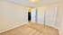 Welcoming bedroom with soft carpet flooring, ample closet space, and a peek into a modern kitchen, perfect for cozy living.