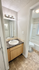 Contemporary bathroom featuring a sleek granite countertop, well-lit vanity mirror, and a clean, modern bathtub.