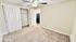 Bright and cozy bedroom with plush carpet, sliding closet doors, and a ceiling fan, leading into a modern kitchen.