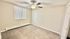 Bright, cozy bedroom with soft carpet, modern ceiling fan, and ample natural light from vertical blinds.
