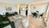 Inviting open-concept living space with elegant green sofa, modern coffee table, and cozy dining area with chic green chairs.