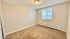 Bright and inviting bedroom featuring plush carpeting, neutral walls, and ample natural light from a large window with blinds.