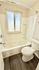 Bright and contemporary bathroom featuring a sleek bathtub, elegant white fixtures, and natural light through a frosted window.