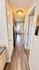 Inviting hallway leading to a modern kitchen with stylish wood flooring and bright lighting.