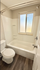 Bright and inviting bathroom featuring a pristine bathtub, modern fixtures, and elegant wood-style flooring.