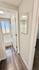 Inviting hallway with rich wood flooring leading to a bright, modern bathroom featuring a window for natural light.