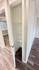 Modern apartment showcasing a sleek storage closet with built-in shelves, elegant laminate flooring, and an inviting open room with natural light.