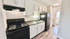 Sleek modern kitchen with white cabinetry and stylish black appliances, perfect for contemporary living.