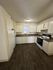 Bright and inviting kitchen with modern white cabinetry, sleek countertops, and stylish dark wood flooring.