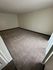 Spacious carpeted room with clean walls, perfect for a cozy living space or bedroom setup.