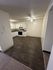 Modern kitchen with dark hardwood flooring, white cabinetry, and ceiling fan, offering a sleek and functional space.