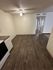 Modern apartment with sleek laminate flooring, open dining area, and bright ceiling fan lighting.