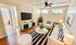 Bright, modern living room with stylish decor, featuring a comfortable white sofa, striped cushions, and lush plants. Natural light streams in through large windows.