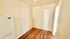 Cozy interior space with warm wooden flooring and neutral walls, featuring a compact fridge in a bright corner.