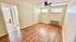 Bright room with warm wood flooring and ceiling fan, featuring a view into a modern tiled bathroom.