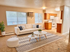 Inviting living room with stylish white sofa, cozy area rug, and modern coffee tables, adjacent to a compact kitchen with wooden cabinetry and white appliances.