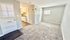 Bright living space with plush carpeting opens to a compact, modern kitchen featuring sleek cabinetry and a cozy cooking area.