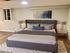 Elegant bedroom featuring a plush queen-sized bed with stylish cushions, sleek nightstands with modern lamps, and a chic abstract artwork above the bed.