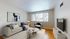 Cozy contemporary living room with elegant decor, featuring a comfortable sofa, modern armchair, stylish coffee tables, and a large window illuminating the space with natural light.