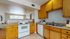 Inviting kitchen with warm wooden cabinetry, modern appliances, and a cozy open layout connecting to a bright living area.