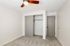 Bright and cozy bedroom with plush carpet, sleek ceiling fan, and spacious sliding closet for ample storage.