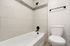 Modern bathroom featuring sleek white tiles, stylish bathtub, and contemporary fixtures.
