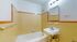 Charming bathroom featuring vintage yellow tile, a cozy bathtub, and a sleek wall-mounted sink.