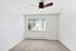 Bright and spacious room with plush carpeting, modern ceiling fan, and large window offering natural light.
