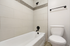 Modern bathroom featuring a stylish bathtub with elegant tile backsplash and a pristine toilet.