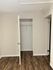 Modern apartment room with elegant wood flooring and a spacious open closet, perfect for organizing wardrobe essentials.