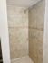 Elegant bathroom shower with stylish beige tiles and intricate border design.