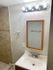 Bright and modern bathroom featuring elegant lighting, a stylish mirror, and a sleek wall-mounted sink.