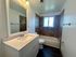 Chic modern bathroom featuring elegant marble countertop, large framed mirror, and stylish tiled bathtub with natural light.