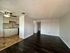 Inviting open-plan apartment with modern kitchen, elegant cabinetry, and sleek dark hardwood floors adjacent to living area.