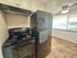 Chic kitchen featuring modern black appliances, elegant tile flooring, and bright natural light through large windows.
