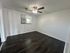 Bright, inviting room with modern dark wood flooring and ceiling fan, perfect for a cozy living space.