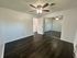 Bright and spacious room with dark hardwood flooring, mirrored closet doors, and a ceiling fan.