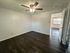 Spacious room with elegant dark wood flooring, ceiling fan, and ample natural light through open doorway.