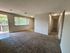 Bright living room with plush carpet and large window, featuring open access to balcony and hallway.