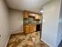 Charming kitchen with elegant wood cabinetry, granite backsplash, and tiled floor, offering a warm and inviting atmosphere.
