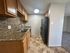 Modern kitchen with granite countertops, wood cabinetry, and sleek appliances leading to a cozy living area.