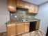 Modern kitchen with sleek granite countertops, wooden cabinets, and black appliances in a stylish apartment setting.