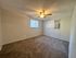 Spacious bedroom featuring plush carpeting, natural light from two windows, and a ceiling fan for comfort.