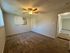 Cozy bedroom with plush carpeting, ceiling fan, and natural light from a window air conditioner unit.