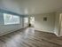 Bright and spacious living area with large windows and sleek wood flooring, offering a modern and inviting atmosphere.