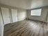 Bright and spacious room with modern wood flooring and large window inviting natural light.