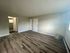 Spacious room with elegant wood flooring and natural light, featuring neutral walls and open doorway design.