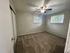 Bright and inviting bedroom with large windows, fresh carpet, and ceiling fan, perfect for a cozy retreat.