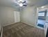 Inviting bedroom with plush carpet, ceiling fan, and ample natural light through adjacent window. Open doorway leading to bright living space.