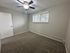 Bright and inviting bedroom with plush carpet, ceiling fan, and a large window providing natural light.